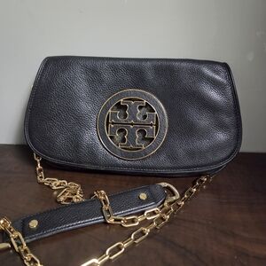 Amanda / logo flap clutchColor: Black pebbled leather with gold‑tone hardware
